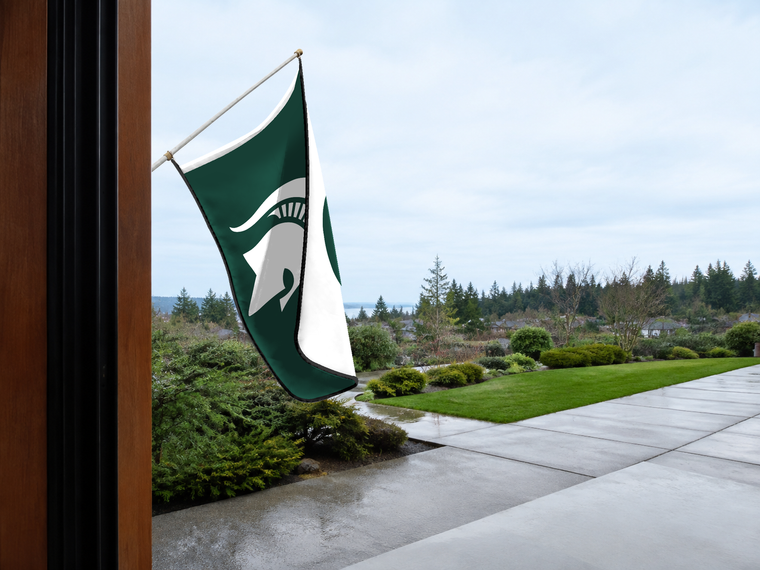 Michigan State Spartans Authentic Gameday Flag — approved one-scene environment view — EXO R89 — item_id=ncaa-fbs-michigan-state-spartans — source_sha256=05d1468de6d5ce6fc3caee1ebb8d2a601e37d3984e27bbf324ad72780672ee6c