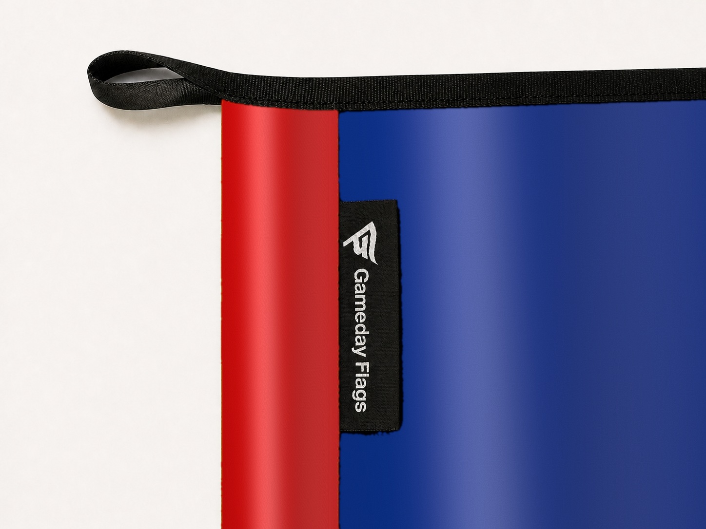 Buffalo Bills Authentic Gameday Flag construction detail — restrained woven-satin Buffalo Bills Accent sewn header, textured Buffalo Bills Primary face, woven Gameday Flags tag, black loop, perimeter webbing, and stitching — source_sha256=4061a01dca7c31b5e30486629a6a2060dfb32bf89ddbe1e3b39ac9aa218882ff