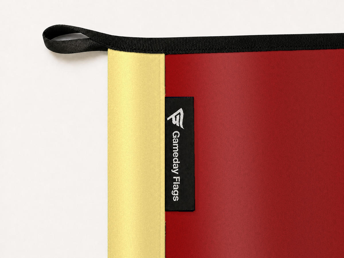 Barcelona Authentic Gameday Flag construction detail — restrained woven-satin Barcelona Accent sewn header, textured Barcelona Primary face, crisp woven Gameday Flags tag and controlled contact shadow, black loop, perimeter webbing, and stitching — source_sha256=bd72cfbe9b73da78b06f50b6ac6609fe5ffcf0d6ad462c754229457040d99f2b