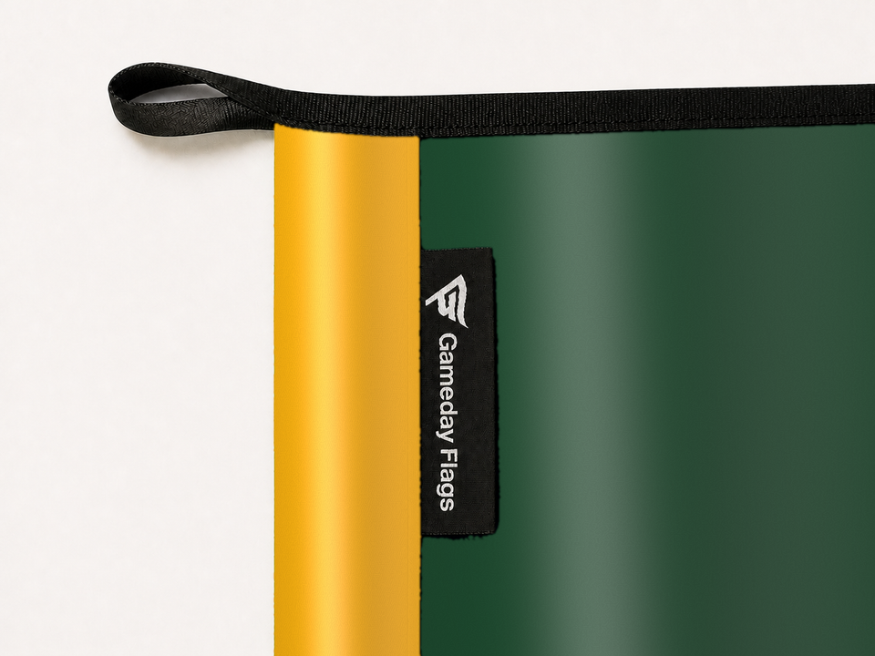 Green Bay Packers Authentic Gameday Flag construction detail — restrained woven-satin Green Bay Packers Accent sewn header, textured Green Bay Packers Primary face, woven Gameday Flags tag, black loop, perimeter webbing, and stitching — source_sha256=97555998d081ae7863330b29dc718c63413085d1d9388926cb0ef1e5c52a963e