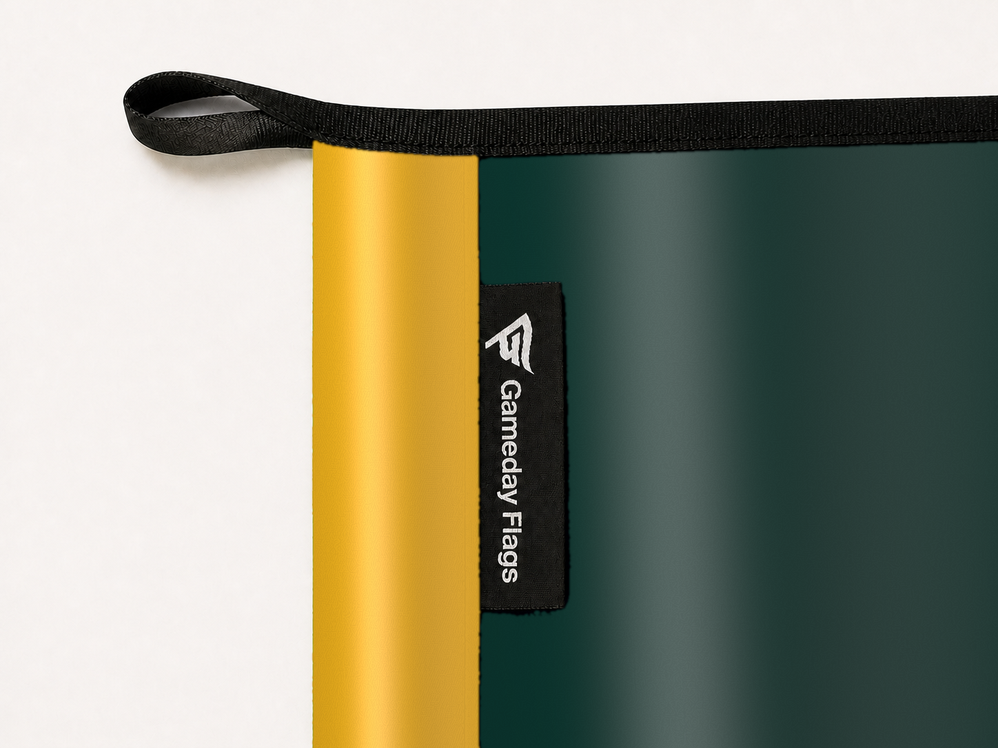 Athletics Authentic Gameday Flag construction detail — restrained woven-satin Athletics Accent sewn header, textured Athletics Primary face, woven Gameday Flags tag, black loop, perimeter webbing, and stitching — source_sha256=29427ebadc25d7b9d8ec8ae646a49d4358d4f342e7ff038e493de4557fa74903