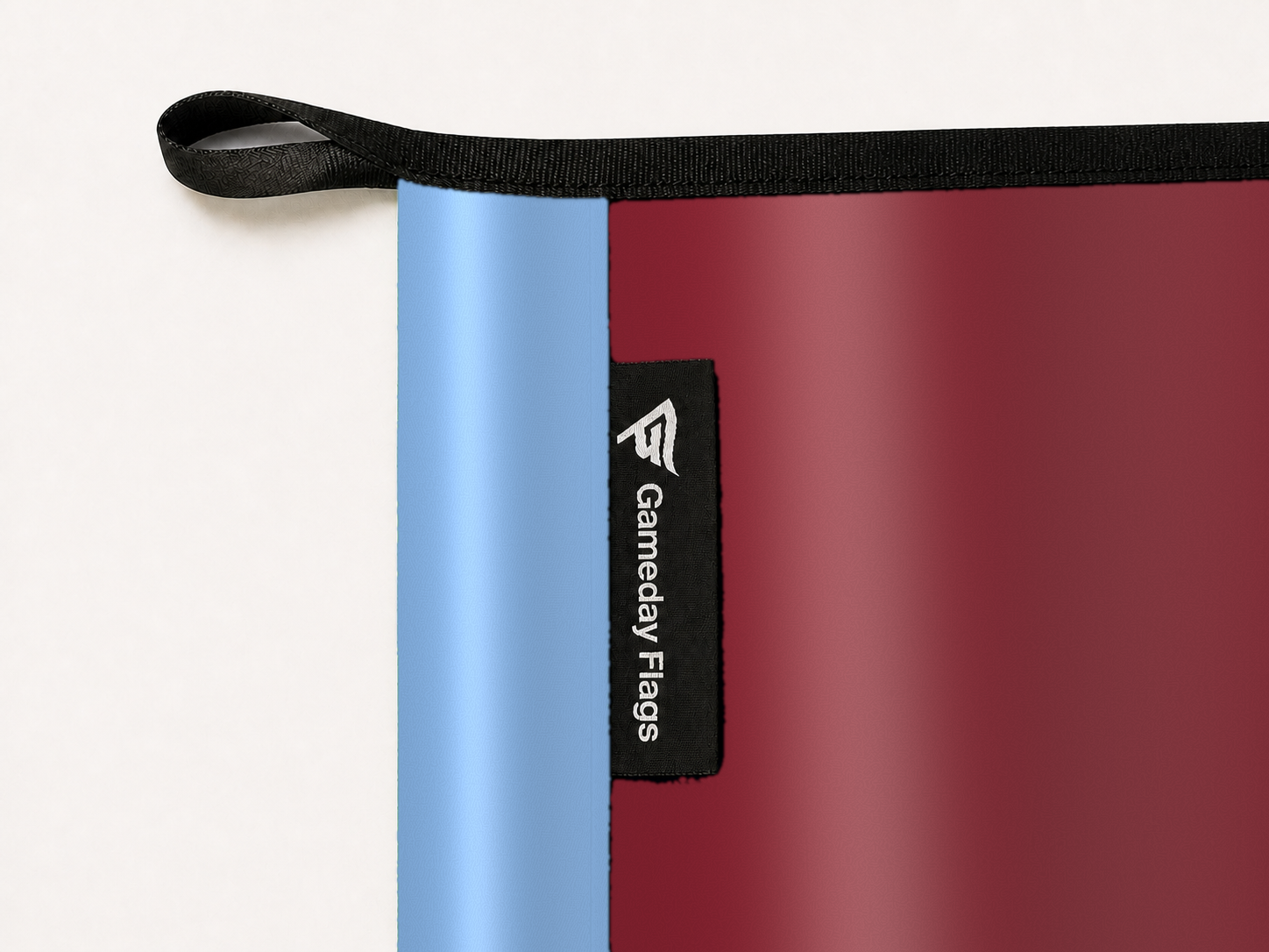 Colorado Rapids Authentic Gameday Flag construction detail — restrained woven-satin Colorado Rapids Accent sewn header, textured Colorado Rapids Primary face, woven Gameday Flags tag, black loop, perimeter webbing, and stitching — source_sha256=975fe80a989831716f185edf42f0daf2ae5eddfc55ec931d3cac078f99b1e909