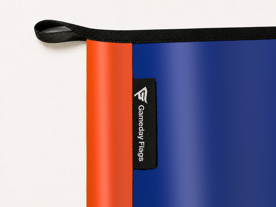 FC Cincinnati Authentic Gameday Flag construction detail — restrained woven-satin FC Cincinnati Accent sewn header, textured FC Cincinnati Primary face, woven Gameday Flags tag, black loop, perimeter webbing, and stitching — source_sha256=17b8516153f73cc411f8af373336bfe4bf3a4f0b755e6932f451e3a40a8cfc0d
