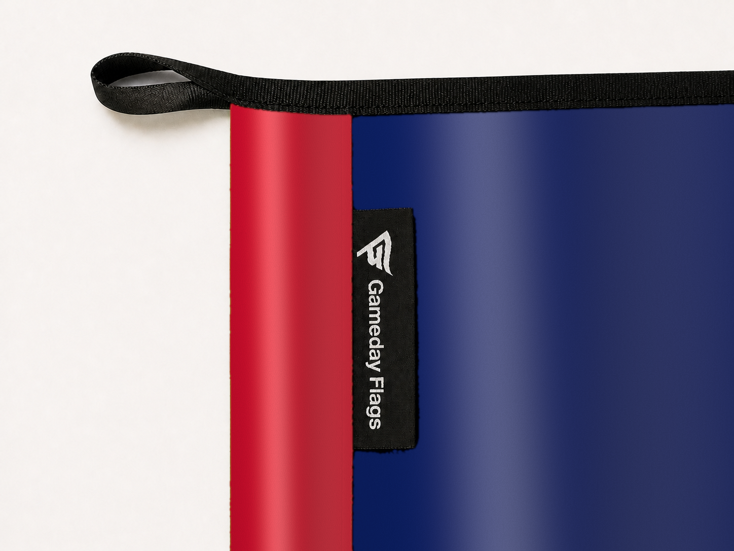 New England Revolution Authentic Gameday Flag construction detail — restrained woven-satin New England Revolution Accent sewn header, textured New England Revolution Primary face, woven Gameday Flags tag, black loop, perimeter webbing, and stitching — source_sha256=856728f1589cf37214684fa330c9970d8b3183921a455d8e26ea809a94fb5143