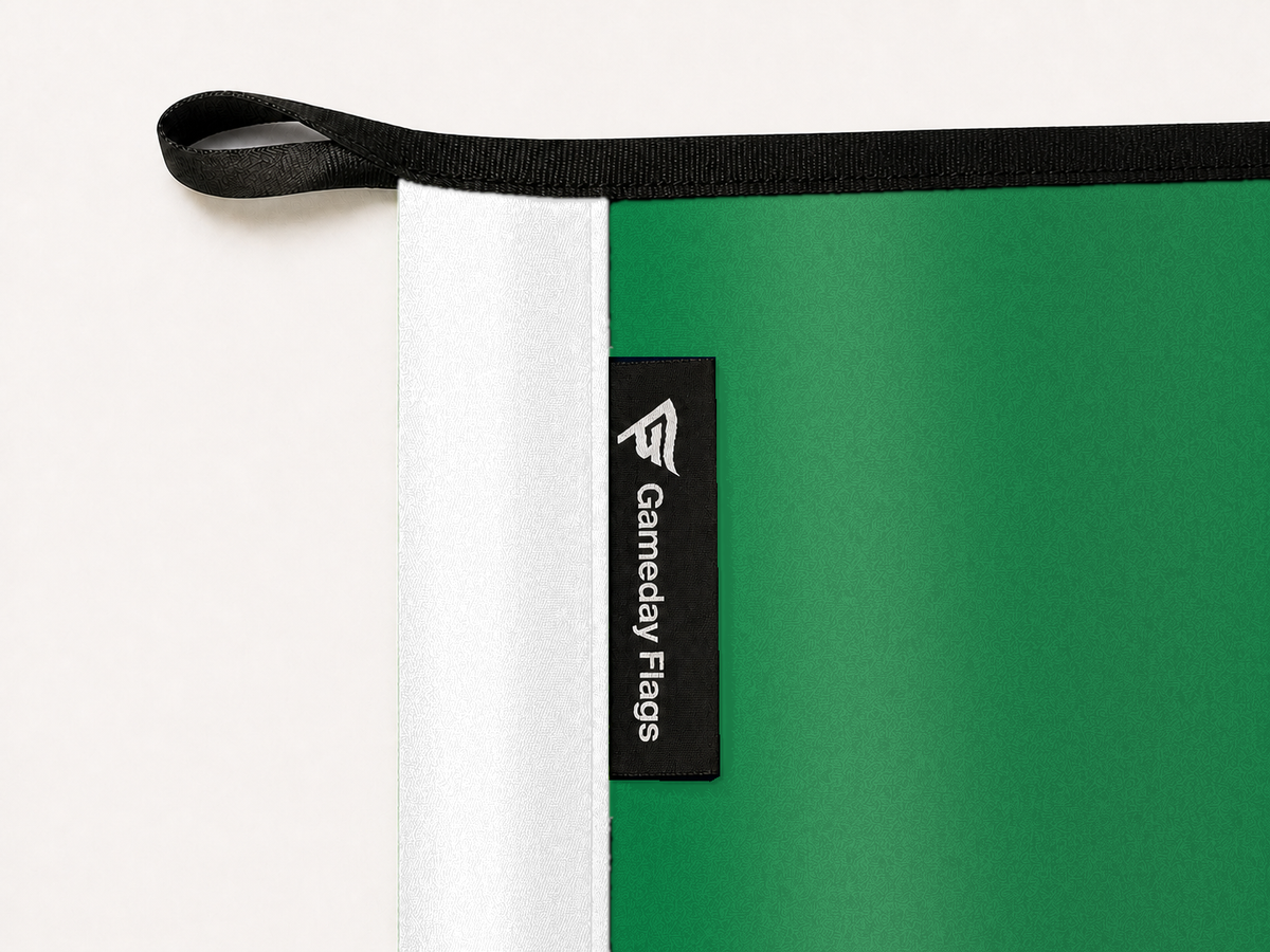 Boston Celtics Authentic Gameday Flag construction detail — restrained woven-satin Boston Celtics Accent sewn header, textured Boston Celtics Primary face, crisp woven Gameday Flags tag and controlled contact shadow, black loop, perimeter webbing, and stitching — source_sha256=5327bdac7f53e81a82464557477df1c74bf850ebcbd6feb64ed2eddefc34cdfe