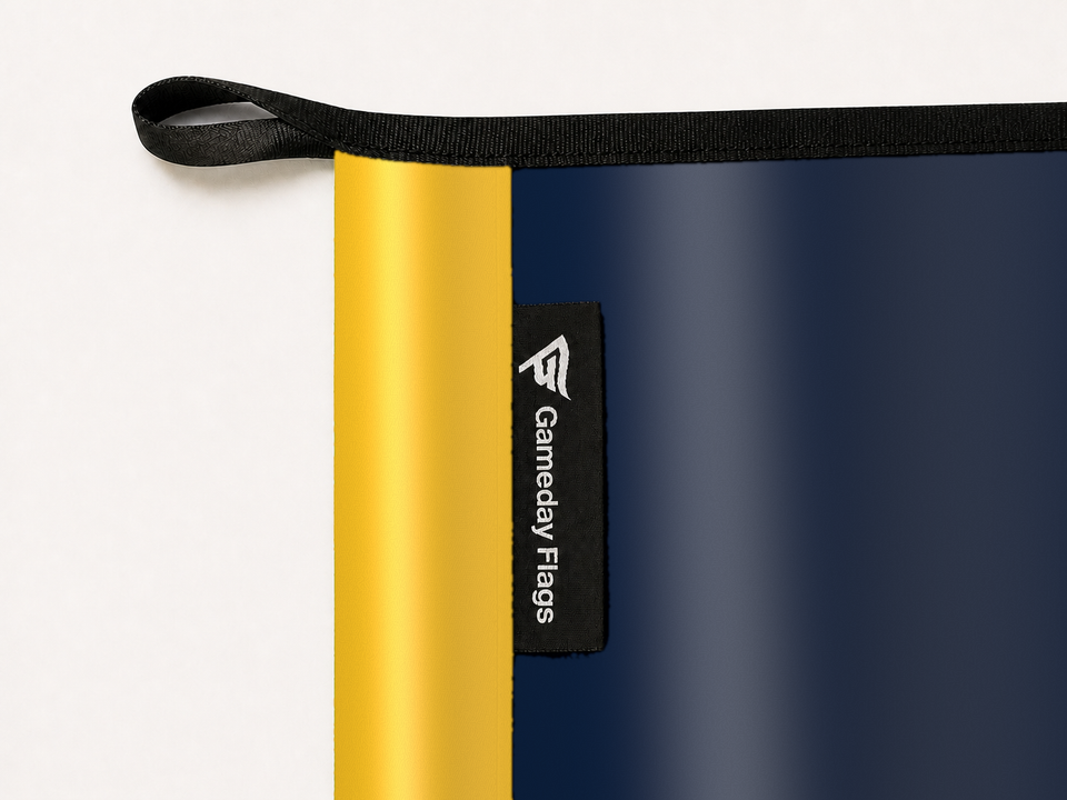 Denver Nuggets Authentic Gameday Flag construction detail — restrained woven-satin Denver Nuggets Accent sewn header, textured Denver Nuggets Primary face, woven Gameday Flags tag, black loop, perimeter webbing, and stitching — source_sha256=734160f1d6c01c9664935228c615e132220e9f6b5a57209396ff7192a37adbd0
