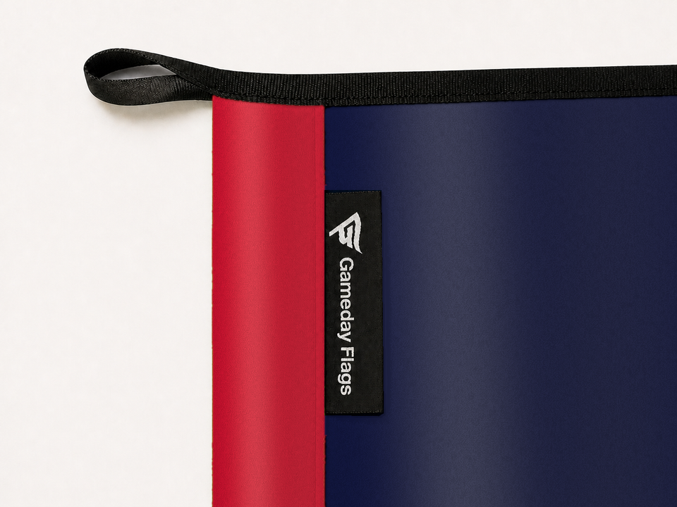 LA Clippers Authentic Gameday Flag construction detail — restrained woven-satin LA Clippers Accent sewn header, textured LA Clippers Primary face, crisp woven Gameday Flags tag and controlled contact shadow, black loop, perimeter webbing, and stitching — source_sha256=f1f164bd2e7e1b45f726f0959544b2da633833b13736380badb70fffc4e96fae
