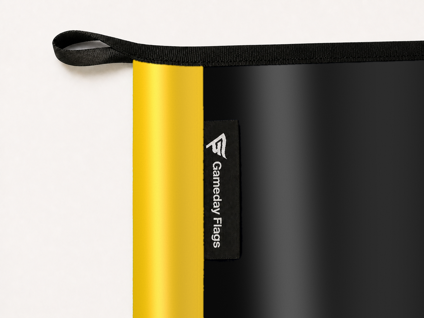App State Mountaineers Authentic Gameday Flag construction detail — restrained woven-satin App State Mountaineers Accent sewn header, textured App State Mountaineers Primary face, woven Gameday Flags tag, black loop, perimeter webbing, and stitching — source_sha256=d53115abcc4d118be4f8d502f5c9dca2cd8833b92e6391f7c9fce9f65c2a06ec