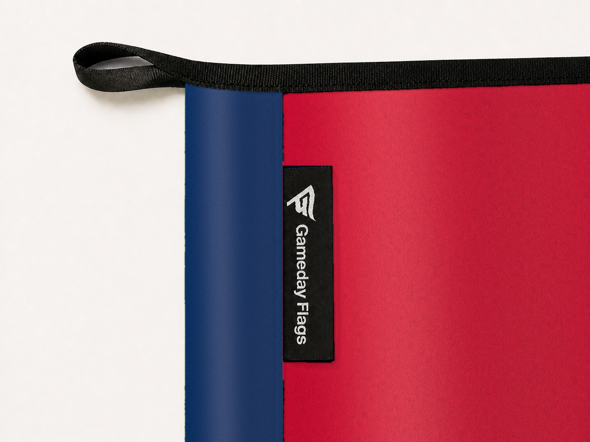 Arizona Wildcats Authentic Gameday Flag construction detail — restrained woven-satin Arizona Wildcats Accent sewn header, textured Arizona Wildcats Primary face, crisp woven Gameday Flags tag and controlled contact shadow, black loop, perimeter webbing, and stitching — source_sha256=44c0653afb9c10b00bc1de8903e9a77f306369a6674d21d90d945daeffeab3d7