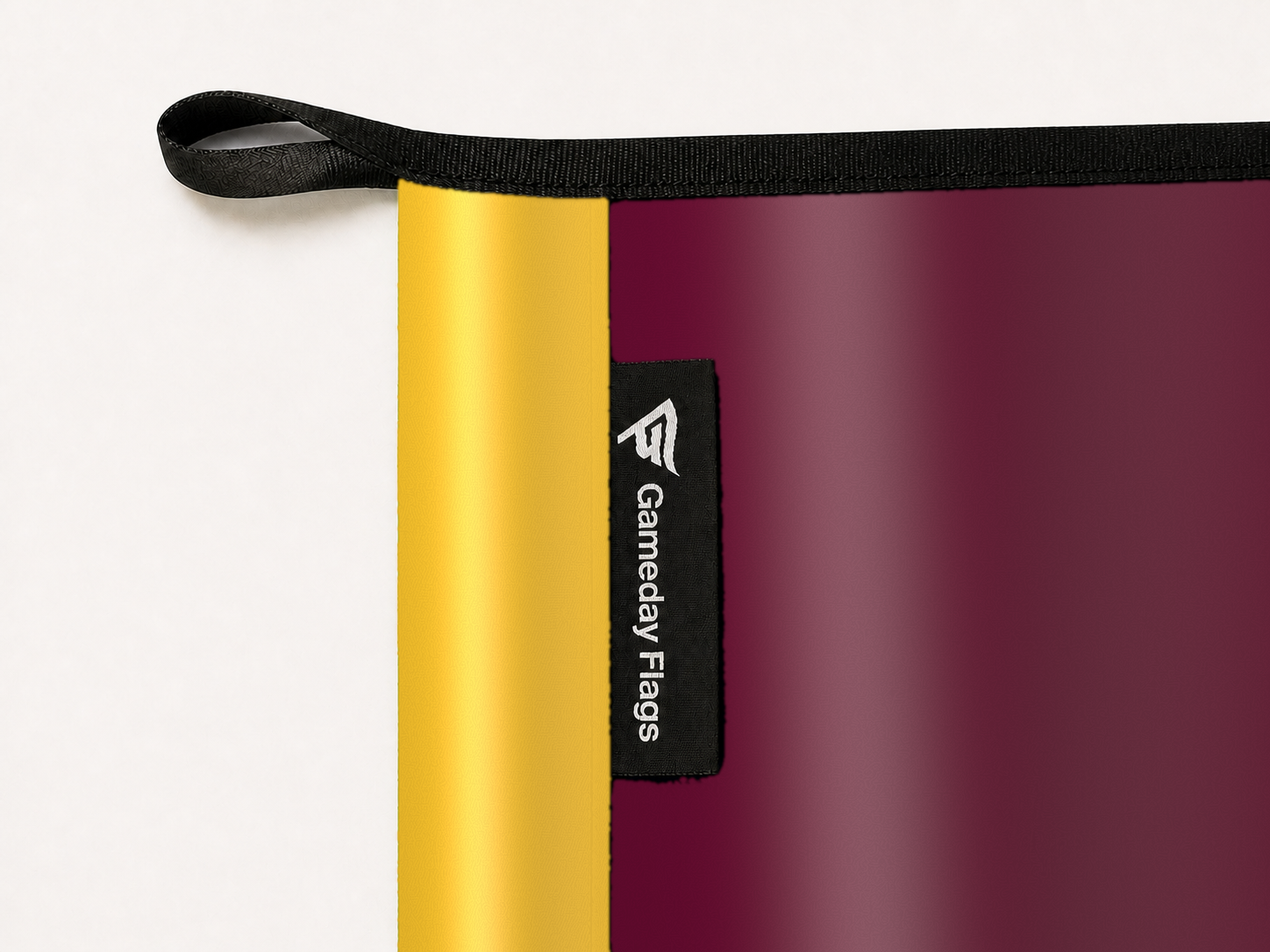 Central Michigan Chippewas Authentic Gameday Flag construction detail — restrained woven-satin Central Michigan Chippewas Accent sewn header, textured Central Michigan Chippewas Primary face, woven Gameday Flags tag, black loop, perimeter webbing, and stitching — source_sha256=d736bdc57e202e0d4e54ca1699db3c40094001db235fc5afa6779d811d922dd6