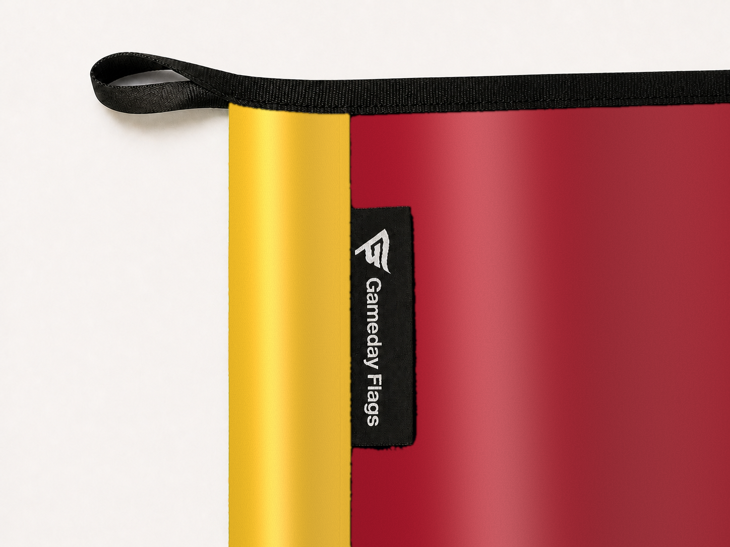 Iowa State Cyclones Authentic Gameday Flag construction detail — restrained woven-satin Iowa State Cyclones Accent sewn header, textured Iowa State Cyclones Primary face, woven Gameday Flags tag, black loop, perimeter webbing, and stitching — source_sha256=bd5e06aa1c697f5b254d22b073e861201ed93579397911e8bd27df0a02c905f2
