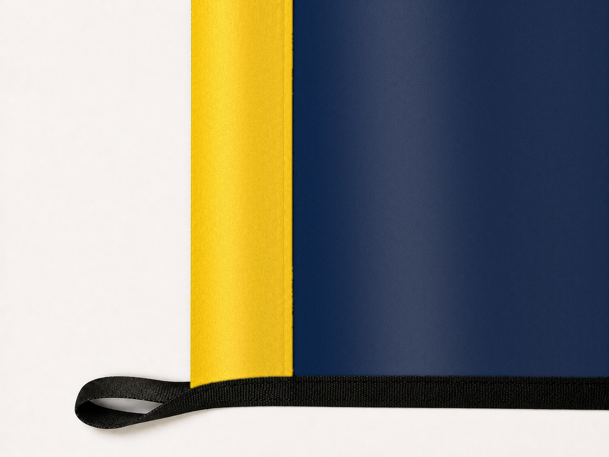 Michigan Wolverines Authentic Gameday Flag underside and personalization construction view — continuous restrained woven-satin Michigan Wolverines Accent header, textured Michigan Wolverines Primary face, lower black loop and perimeter webbing — source_sha256=c102876e956775d2a2ebfdc5bd53bb114cbe6b5adc600ed8945005670d4d7001