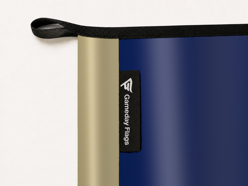 Navy Midshipmen Authentic Gameday Flag construction detail — restrained woven-satin Navy Midshipmen Accent sewn header, textured Navy Midshipmen Primary face, woven Gameday Flags tag, black loop, perimeter webbing, and stitching — source_sha256=91eefbb8628cb30d01b7ec2bcc55a4dfbfad5247c3d21544f0a932d6fc941f9e