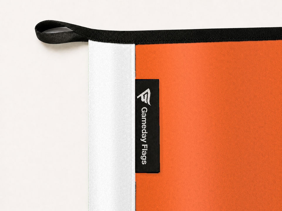 Sam Houston Bearkats Authentic Gameday Flag construction detail — restrained woven-satin Sam Houston Bearkats Accent sewn header, textured Sam Houston Bearkats Primary face, crisp woven Gameday Flags tag and controlled contact shadow, black loop, perimeter webbing, and stitching — source_sha256=9fbecca33cc8a9dee1a56566ceb739cd17551dbaaa06908153f76465d559fce1