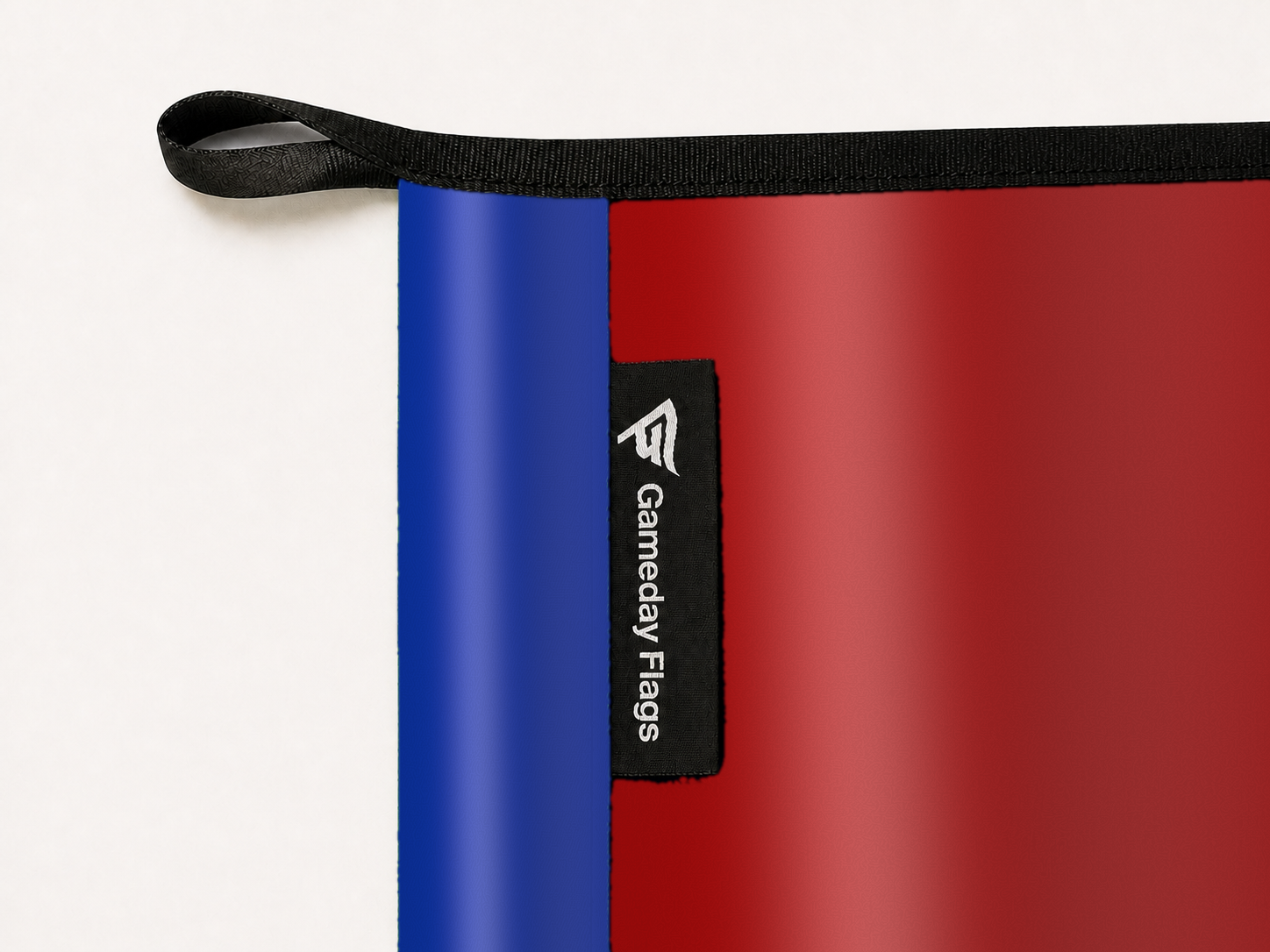 SMU Mustangs Authentic Gameday Flag construction detail — restrained woven-satin SMU Mustangs Accent sewn header, textured SMU Mustangs Primary face, woven Gameday Flags tag, black loop, perimeter webbing, and stitching — source_sha256=3f7354c62044d503539c20e8b896a02e9ed78ea204788b0df1475d3aff6585e9