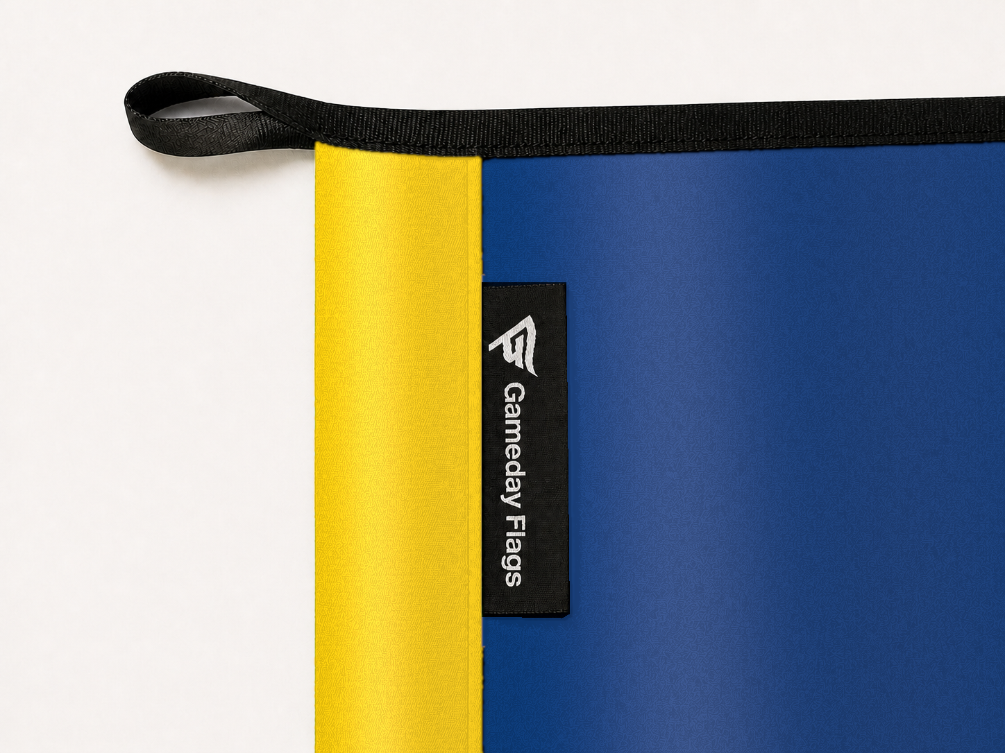 Toledo Rockets Authentic Gameday Flag construction detail — restrained woven-satin Toledo Rockets Accent sewn header, textured Toledo Rockets Primary face, woven Gameday Flags tag, black loop, perimeter webbing, and stitching — source_sha256=097a6f90cd70b52820b6278b449fe690ac1f79a54f90be29e8291db4e9b561cd