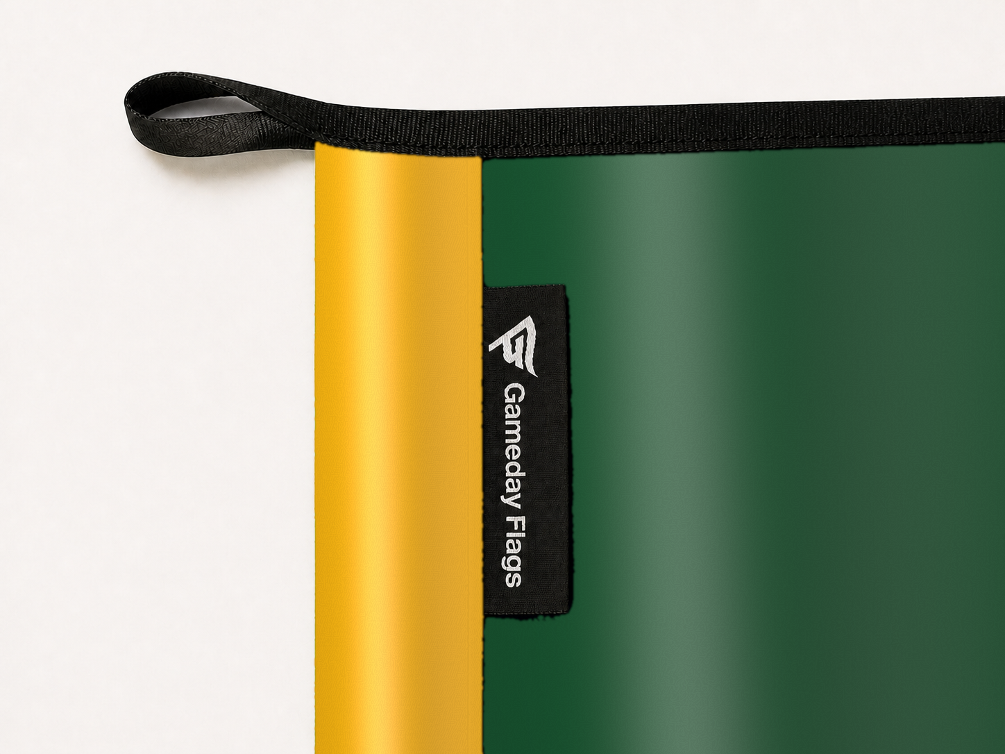 UAB Blazers Authentic Gameday Flag construction detail — restrained woven-satin UAB Blazers Accent sewn header, textured UAB Blazers Primary face, woven Gameday Flags tag, black loop, perimeter webbing, and stitching — source_sha256=55606a3b198885762b28e5f5ccbedb3d3e128976bc5ad70bf0524b549bd60119