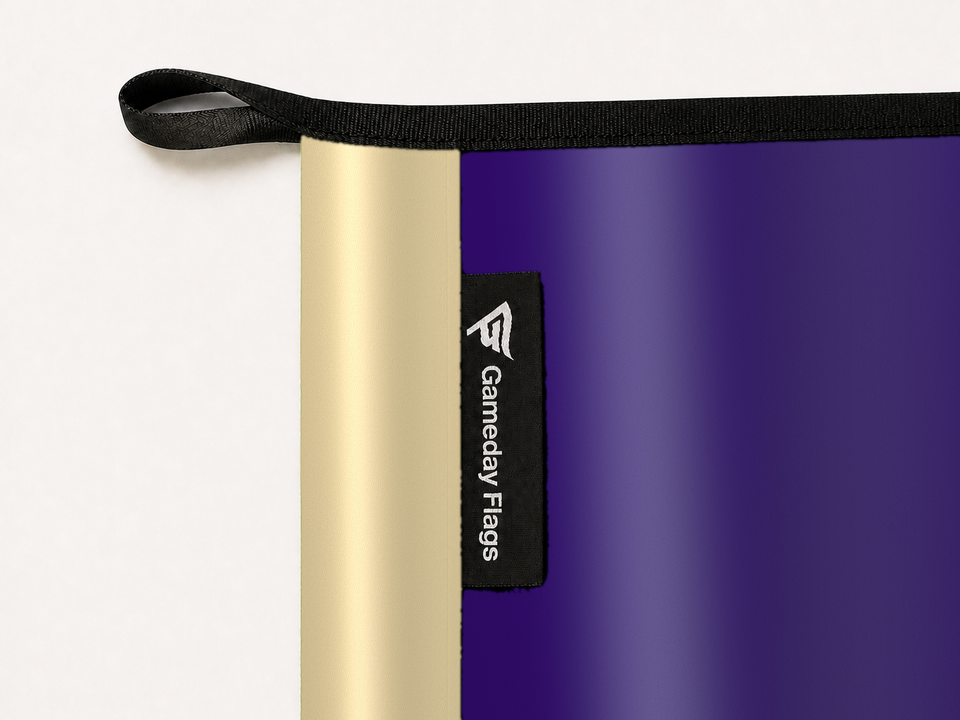 Washington Huskies Authentic Gameday Flag construction detail — restrained woven-satin Washington Huskies Accent sewn header, textured Washington Huskies Primary face, woven Gameday Flags tag, black loop, perimeter webbing, and stitching — source_sha256=bde6fe2c083fa898670cd69dcfcbfd590dd0cc11420328b4ff09c558435e4445