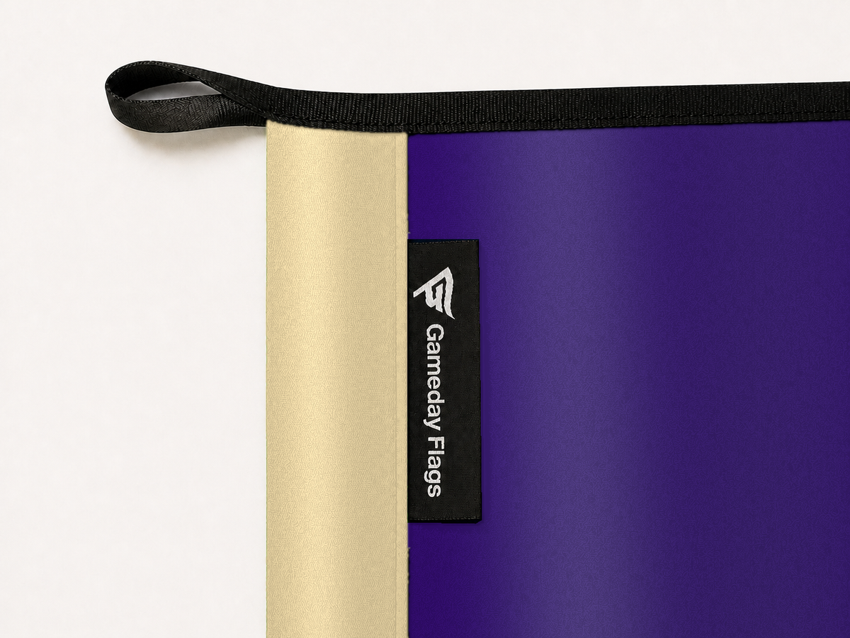Washington Huskies Authentic Gameday Flag construction detail — restrained woven-satin Washington Huskies Accent sewn header, textured Washington Huskies Primary face, crisp woven Gameday Flags tag and controlled contact shadow, black loop, perimeter webbing, and stitching — source_sha256=b258838d08446a5f1fa1b082f1d75172fbdc34d93b51224758da93c4bb6babec