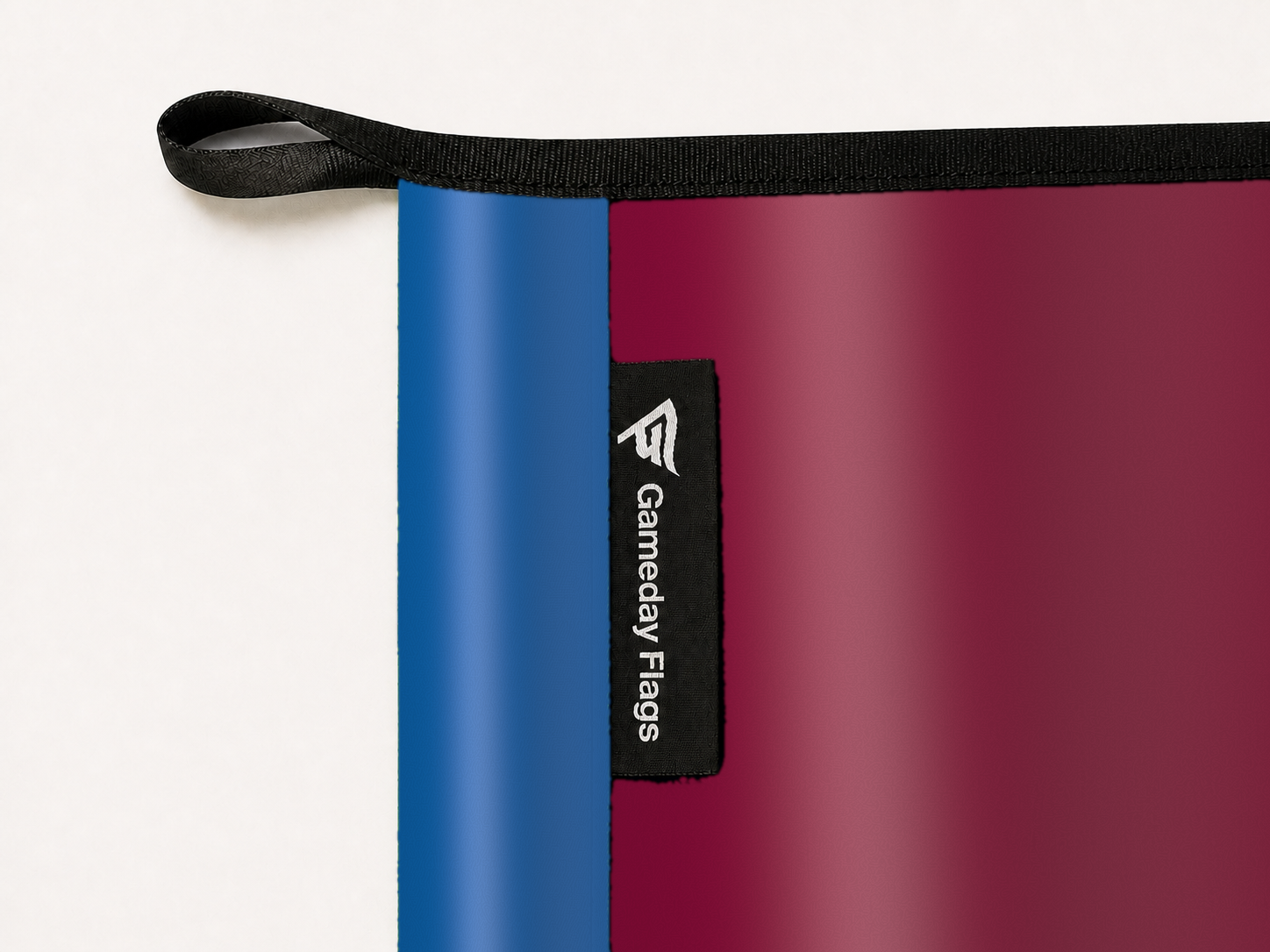 Colorado Avalanche Authentic Gameday Flag construction detail — restrained woven-satin Colorado Avalanche Accent sewn header, textured Colorado Avalanche Primary face, woven Gameday Flags tag, black loop, perimeter webbing, and stitching — source_sha256=761a81f423a9bd7e3aebff6e9e932206df2c2512c0c9365e54787ac7509b7681