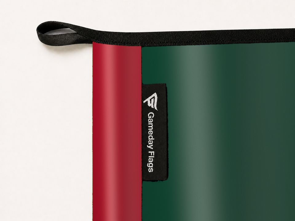 Minnesota Wild Authentic Gameday Flag construction detail — restrained woven-satin Minnesota Wild Accent sewn header, textured Minnesota Wild Primary face, woven Gameday Flags tag, black loop, perimeter webbing, and stitching — source_sha256=d8bf6101a8767282f72dfbbe341cf7dbd502168ca206cdb921d217108c1b440f