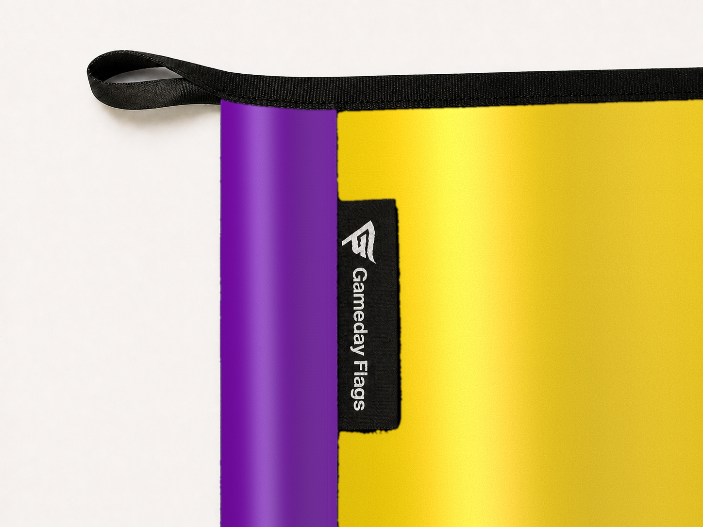 Intersex Flag Authentic Gameday Flag construction detail — restrained woven-satin Intersex Flag Accent sewn header, textured Intersex Flag Primary face, woven Gameday Flags tag, black loop, perimeter webbing, and stitching — source_sha256=ebb4c9c70faf9dcfa56a719d98b1fe0c12f70ae989cb98c53513b4b963057c85