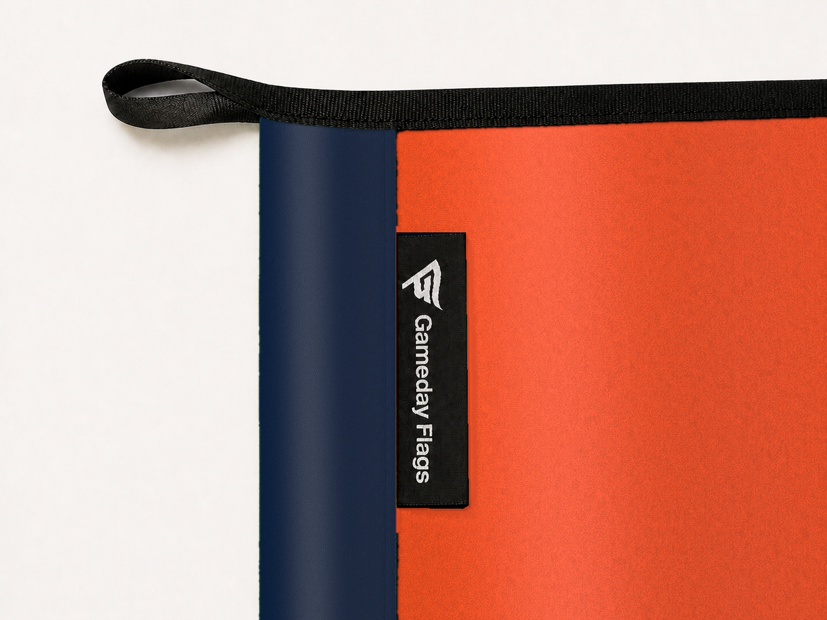 Connecticut Sun Authentic Gameday Flag construction detail — restrained woven-satin Connecticut Sun Accent sewn header, textured Connecticut Sun Primary face, crisp woven Gameday Flags tag and controlled contact shadow, black loop, perimeter webbing, and stitching — source_sha256=1f5ac9d94ed1d2b073ff1a9b14cdea68e355aac19829cb5de7377f9ede6a08e3