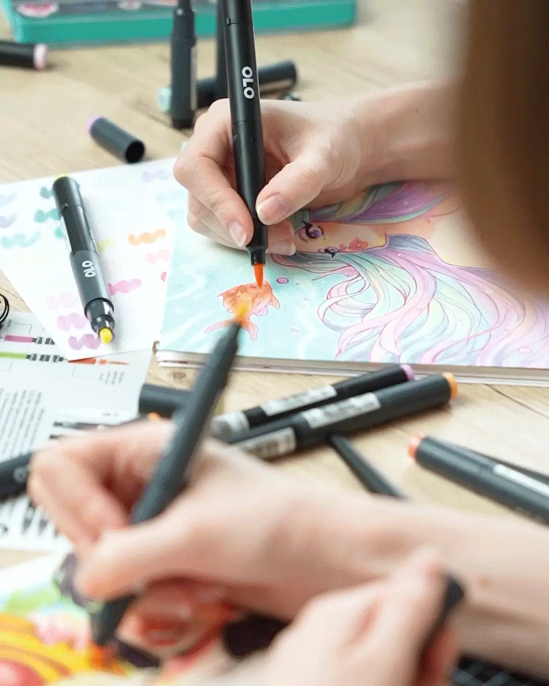 Artists using OLO markers to color bright artwork at a shared table